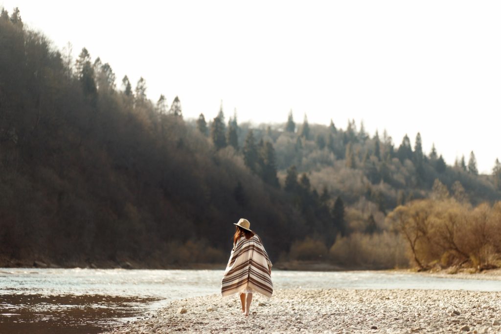 beautiful woman hipster walking on river beach in mountains