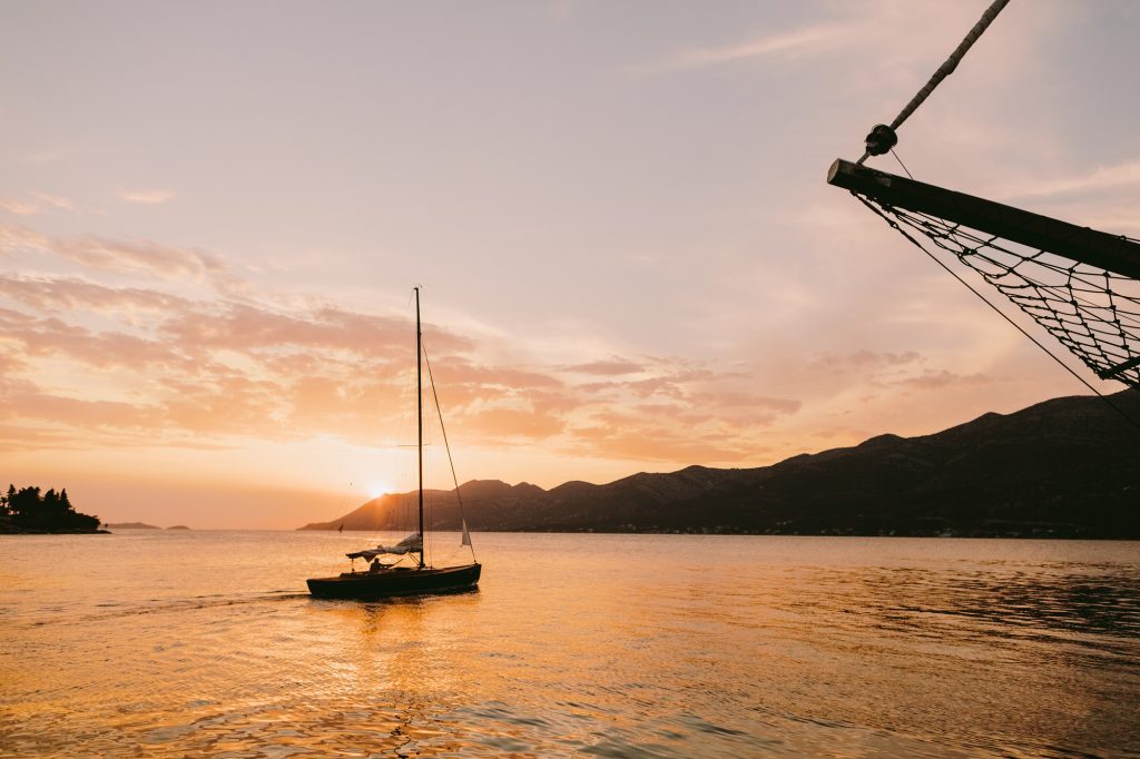 yacht sailing at sunset in sea with mountains view