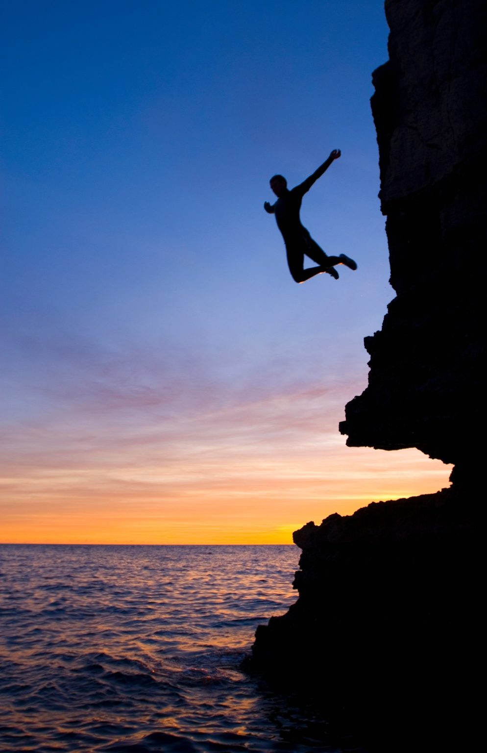 Silhouette of man cliff diving