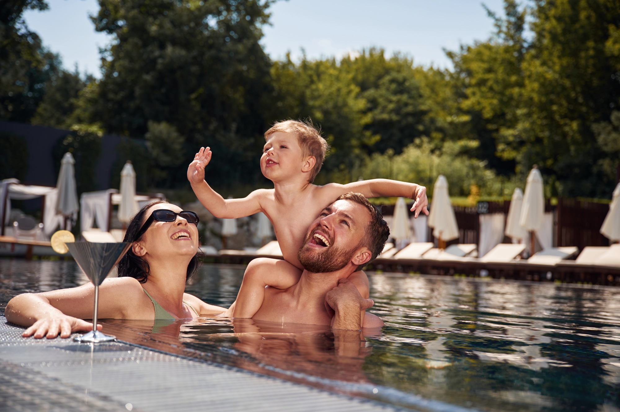 Having fun. Happy family of father, mother and son are in the pool