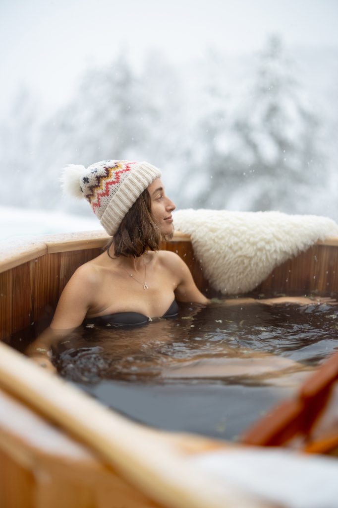 Woman relaxing in hot bath at snowy mountains